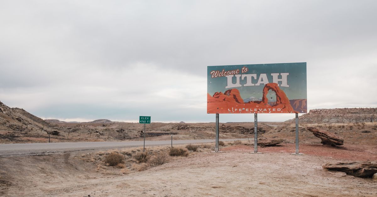 A 'Welcome to Utah' sign with desert landscape background under a cloudy sky.